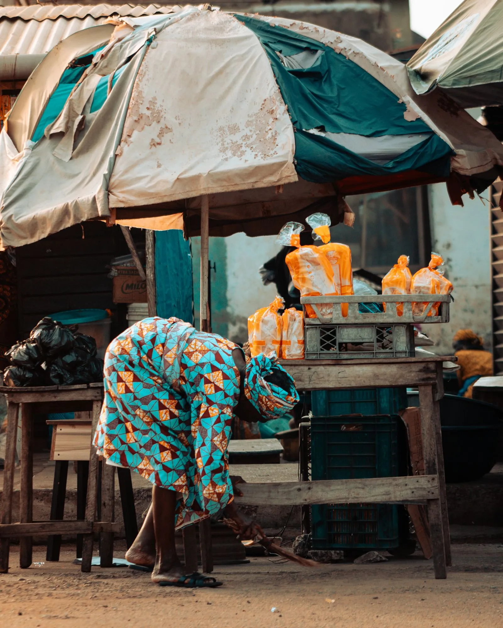 A vendor in a patterned wrapper sets up her street stall in Lagos