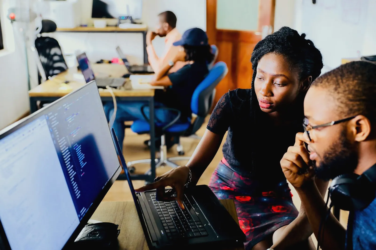 Two colleagues in a Lagos workspace review work together on a laptop