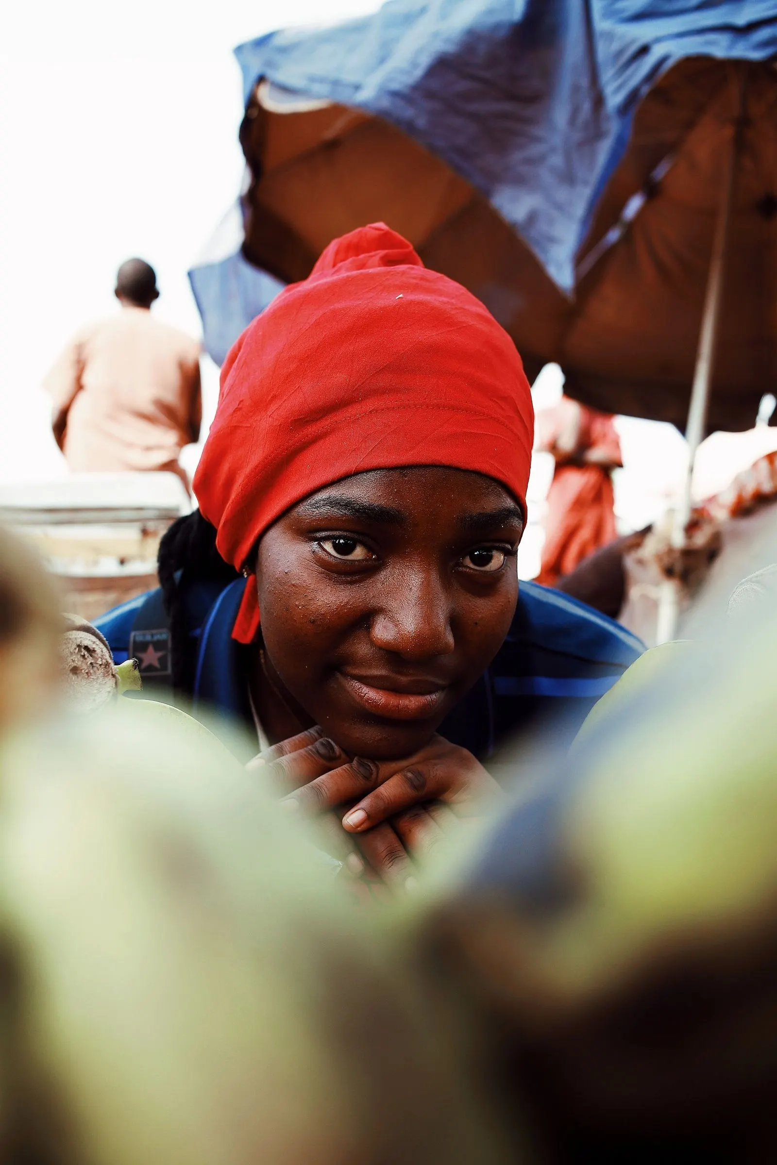 A market vendor in Abuja in a red headscarf looks into the camera