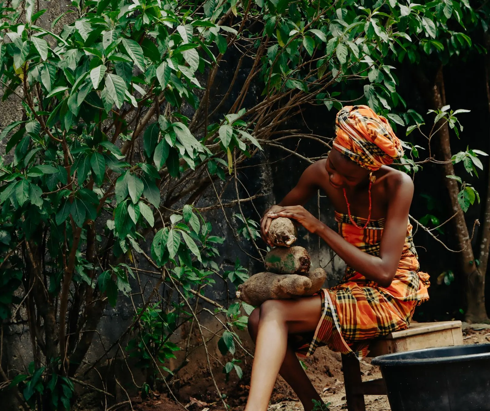 A woman in traditional dress prepares harvested yams outdoors